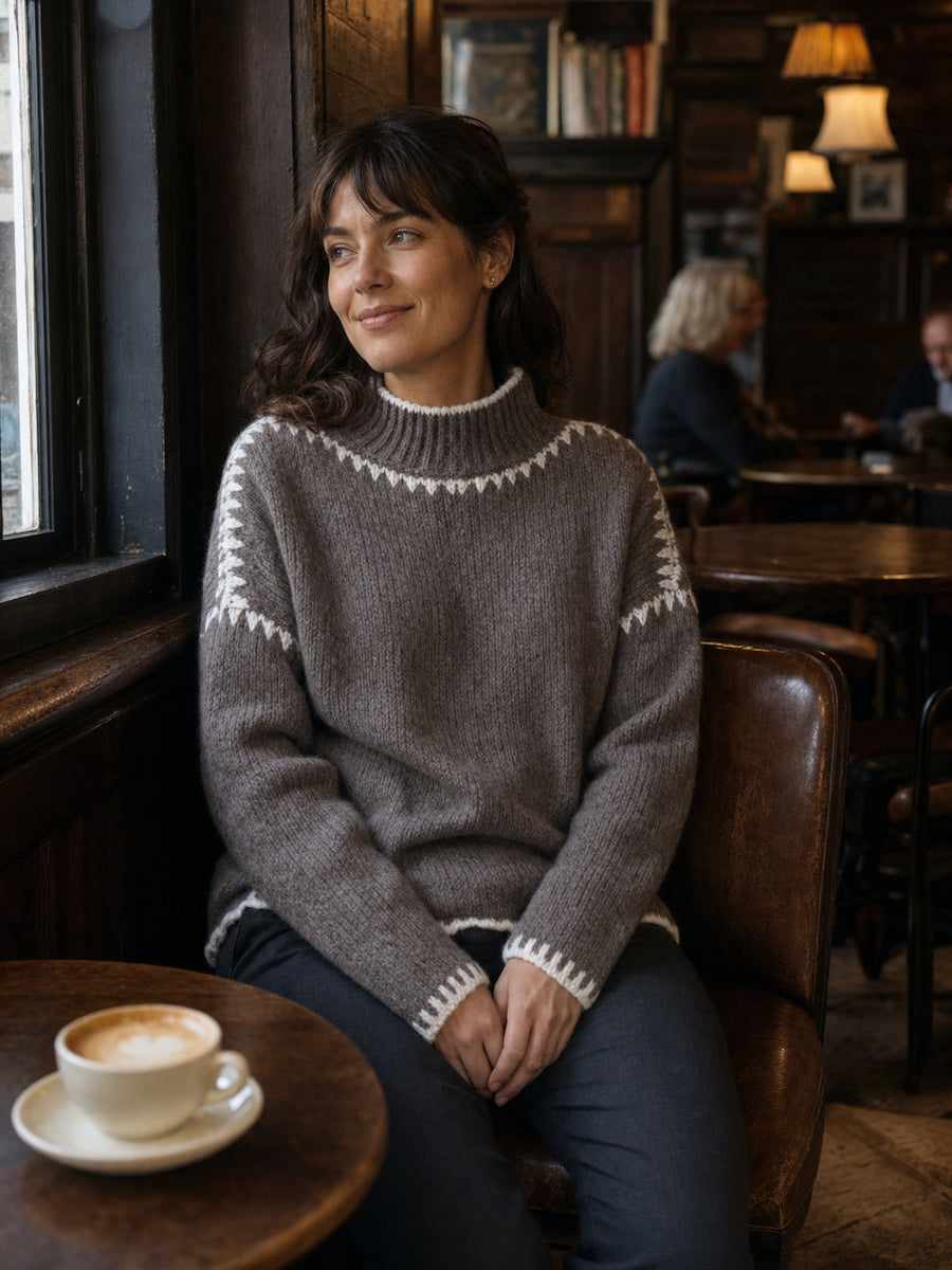 Frau im Strickpullover Jolie in Dark Taupe von Seasons of April an einem Caféfenster